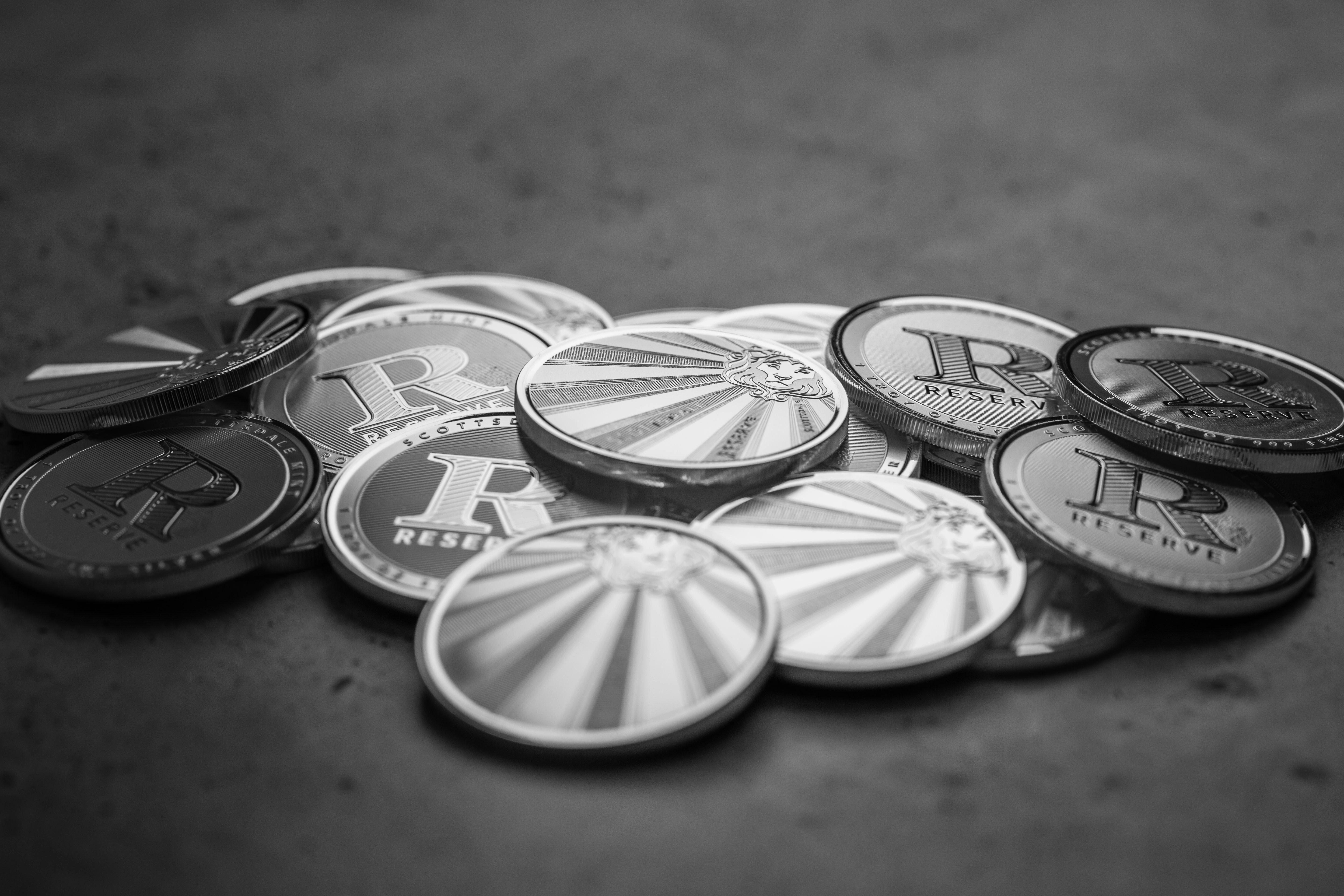 Scottsdale Mint Reserve Bullion rounds sitting on a textured table. Each coin is 999 Fine and made from silver precious metals. Sitting on a dark textured background. Please give a shoutout to Scottsdale Mint if able! Shop online for the most beautiful bullion at ScottsdaleMint.com!